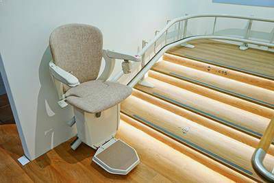Beige stoel van traplift met bocht bovenaan de traplift
